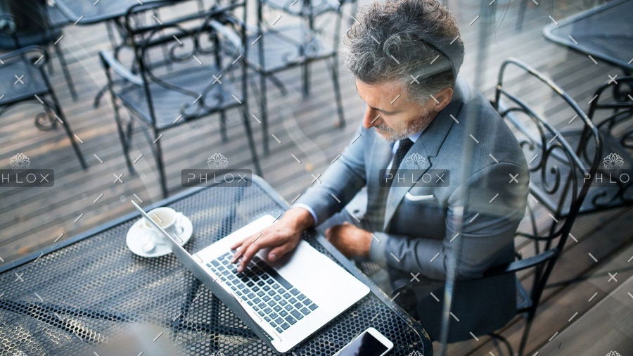 demo-attachment-24-mature-businessman-with-laptop-outside-a-cafe-PXAVBAC